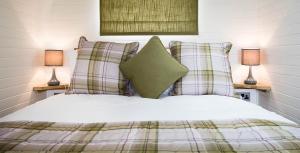 福尔柯克Weedingshall Lodges的一间卧室配有一张带枕头的床和两盏灯。