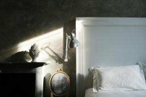 科莫阿布里奇佩雷利尼宫旅馆的一间卧室配有一张床、一盏灯和一面镜子