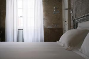 科莫阿布里奇佩雷利尼宫旅馆的卧室配有白色的床和窗户。
