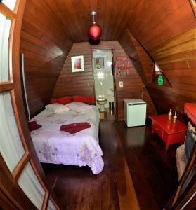 蒙特韦尔迪Pousada Perola da Mantiqueira的木制客房内的一间卧室,配有一张床