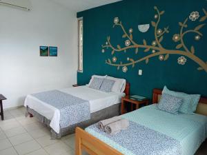 梅里达Casa Del Aire的卧室配有两张床,墙上挂着一幅树壁画