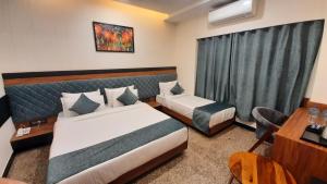 乌代浦Suvin Residency with Rooftop Swimming Pool的酒店客房配有两张床和一张书桌