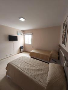 坦季By Muni Apartamentos Premium的一间卧室配有两张床和电视。