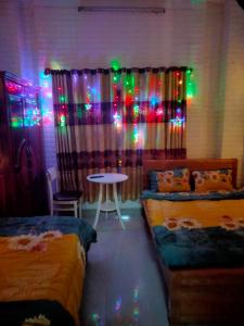 罗夷Tuấn Anh Motel的客房设有两张床和一张带圣诞灯的桌子。