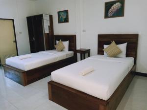 攀牙Rachawadee House的配有白色墙壁的酒店客房内的两张床