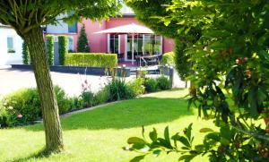 MettendorfHotel Kickert的花园设有粉红色的房子,配有桌子和遮阳伞