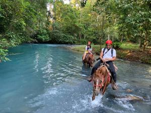 Rio CelesteHotel SueñoReal RioCeleste的两个人骑马过河