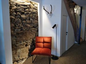 马尔尼茨appartementsKOFLER的石墙旁走廊上的橙色椅子