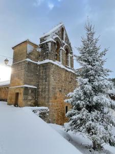 CovaneraHotel Rural Aguazul的教堂前方有雪覆盖的圣诞树