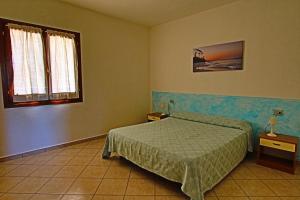 圣特奥多罗Residence Stella Marina的一间卧室设有床、两张桌子和一扇窗户