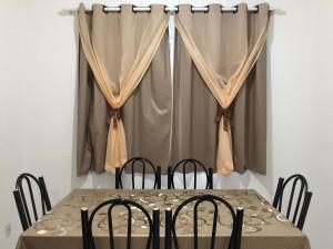 卡拉瓜塔图巴Residencial Martinica I的餐桌、椅子和窗帘