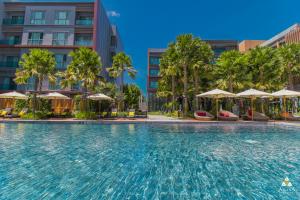 呵叻Aisana Hotel Korat的棕榈树和遮阳伞的酒店游泳池