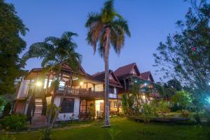 Muang Không肯格马尼克洛尼亚尔旅馆的前面有棕榈树的房子