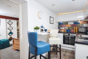 凯格沃思The Little Apartment的厨房配有白色橱柜和蓝色椅子