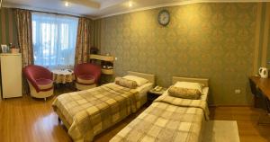 彼尔姆科兹亚玉斯卡酒店的一间卧室设有两张床,墙上挂着一个时钟。