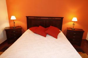 CapeloCasa capelinhos的一间卧室配有一张带红色枕头的床和两盏灯。