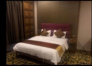 利雅德Hosta Hotel Suites的一间卧室配有一张大床和紫色床头板