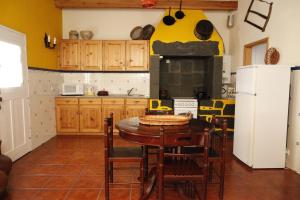 CapeloCasa capelinhos的厨房配有桌椅和冰箱。