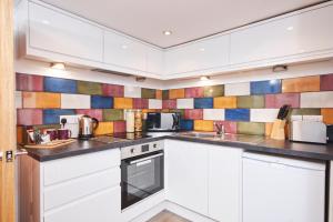 凯格沃思Number 57的厨房配有白色橱柜和彩色的墙壁瓷砖