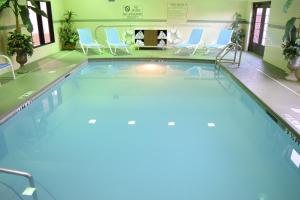 彭萨科拉Holiday Inn Express & Suites Pensacola West I-10, an IHG Hotel的游泳池位于酒店客房内,配有蓝色的椅子和椅子