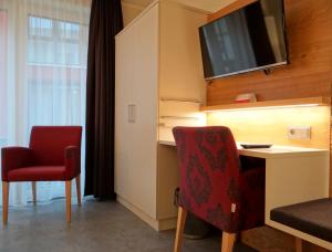 巴特埃森胡歌餐厅酒店的客房设有书桌和墙上的电视