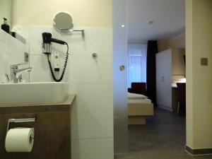 巴特埃森胡歌餐厅酒店的一间带水槽的浴室和墙上的一部电话
