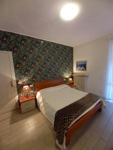 西尔米奥奈Il Nido del Cigno的一间卧室配有一张带花卉壁纸的大床