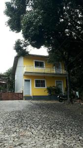 瓜拉米兰加Casa Neto&Lu的前面有一棵树的黄色房子