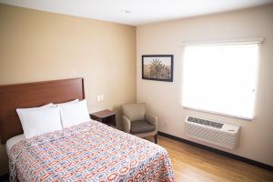 普兰菲尔德白楼套房酒店的一间卧室设有一张床、一个窗口和一把椅子