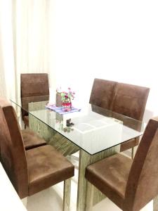 马卡帕Quarto - Condomínio的一张带棕色椅子的玻璃桌和一张带餐桌的玻璃桌