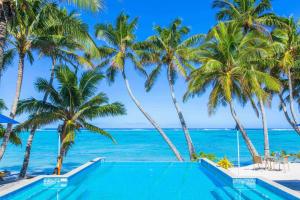 拉罗汤加小玻利尼西亚度假酒店的棕榈树和海洋海滩上的游泳池