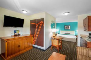 圣乔治Howard Johnson by Wyndham St. George Hotel & Suites的酒店客房设有一间带一张床和一张书桌的卧室