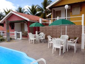 伊塔马拉卡Villa Manary的游泳池旁带桌子和遮阳伞的天井