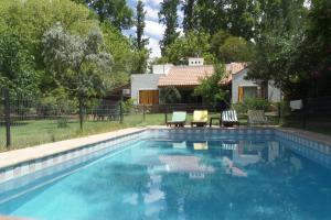 查克拉斯德科里亚La casita en el parque的一个带椅子的游泳池以及一座房子