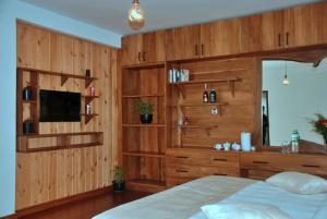 努沃勒埃利耶圣弗朗西斯科度假村的一间卧室设有木墙、一张床和电视。