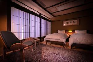 武雄市京都亚酒店的客房设有两张床、椅子和窗户。
