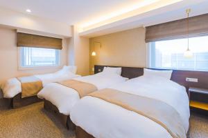 京都M’s Est 四条乌丸酒店的酒店客房设有三张床和窗户。