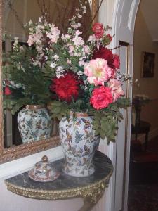 尚克林东山大厅酒店的镜子前的架子上装有鲜花的花瓶