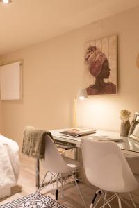 巴塞罗那Chic Apartments Barcelona的客房设有一张带两把椅子的桌子和一幅画