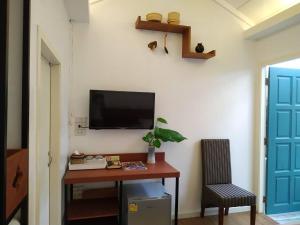 曼谷The Little Cottage 47的客房设有一张桌子,墙上配有电视