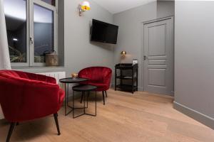 Écurie普拉美&克顿酒店的一间设有两张红色椅子、一张桌子和电视的房间