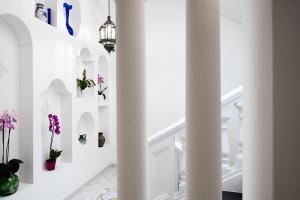 波西塔诺利吉内拉酒店的走廊上设有白色的墙壁和白色的带花瓶的楼梯