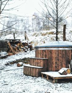 ReguliceLushHills - Tiny House - Modern House On Wheels的雪覆盖的院子,设有木栅栏和长凳