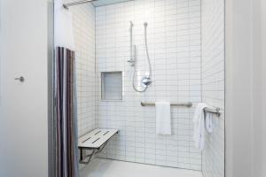 奥兰多TRYP by Wyndham Orlando的白色瓷砖浴室设有长凳和淋浴。