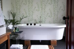 阿宾登椽子住宿加早餐旅馆的浴室设有白色浴缸,配有绿色壁纸