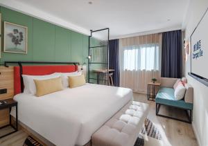 上海康铂上海外滩店的卧室配有一张白色的大床和一张沙发。
