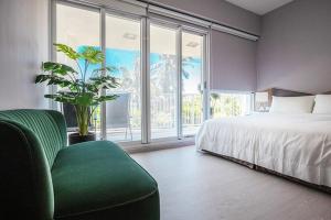 车城墾丁後灣 藍水軒海景民宿的一间卧室设有一张床、一把绿色椅子和大窗户