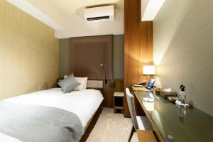 大阪HOTEL HILLARYS Shinsaibashi的配有一张床和一张书桌的酒店客房