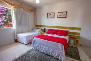 本图贡萨尔维斯卡萨塔斯卡旅馆的一间卧室配有两张带红色枕头的床和窗户。