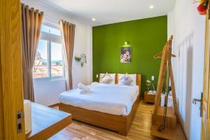 大叻The Green House Da Lat的一间卧室配有一张带绿色墙壁的床